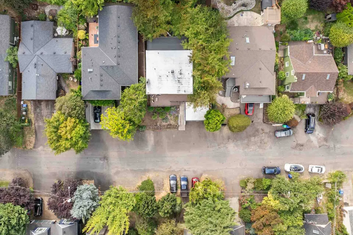 A view of the surrounding neighborhood with plenty of greenery, rooftops of houses, and a peaceful street layout. The image conveys a tranquil residential environment that's perfect for a stroll or a nature walk, with an inviting sense of community.