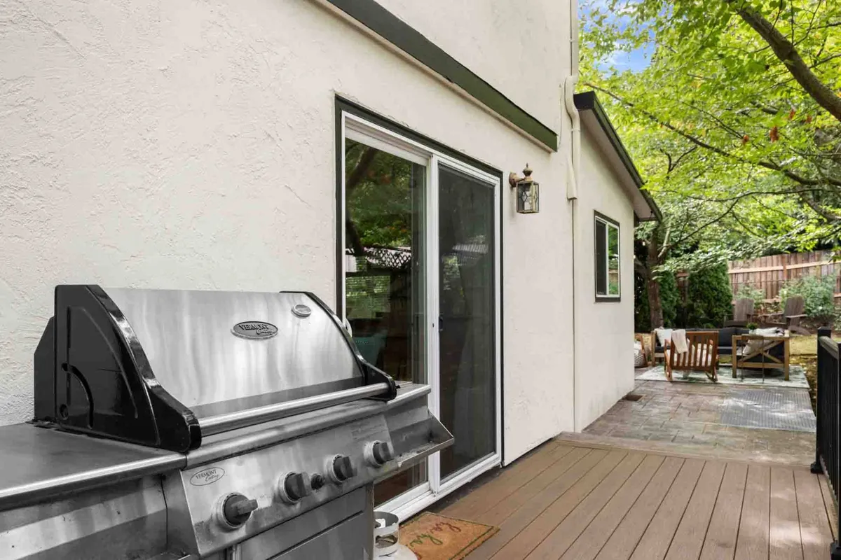 This exterior image focuses on a grill and outdoor seating next to sliding glass doors, suggesting effortless transitions between indoor and outdoor living. It is perfect for barbecuing, evening gatherings, and enjoying relaxed meals under the stars.